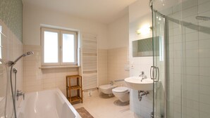 A modern bathroom with a bathtub, a glass-enclosed shower, a toilet, and a sink. - Apartment Hofgarten - Alpstay (Naturno)