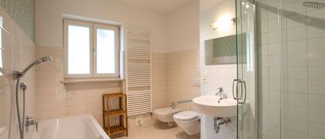 A modern bathroom with a bathtub, a glass-enclosed shower, a toilet, and a sink.