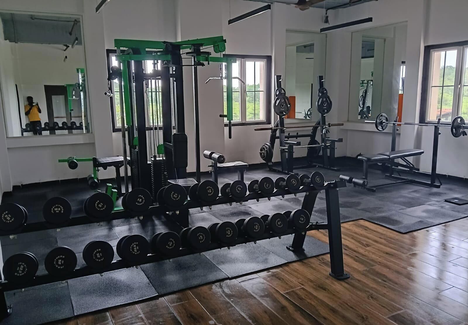 Ein Fitnessstudio mit Gewichthebern, Spiegeln und Holzboden.