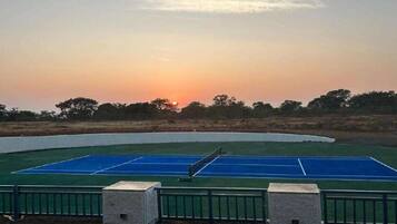 Un campo da tennis con il tramonto sullo sfondo.