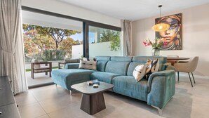 Una sala moderna con un sofá seccional azul, una mesita de centro y un comedor con mesa y sillas.
