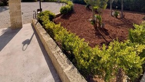 Ein angelegter Gartenbereich mit gepflastertem Weg, einer Steinpfeiler und einem Metalllichtmast.