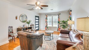 Un salon avec un canapé en cuir marron, une table basse ronde, un ventilateur de plafond et un grand miroir.