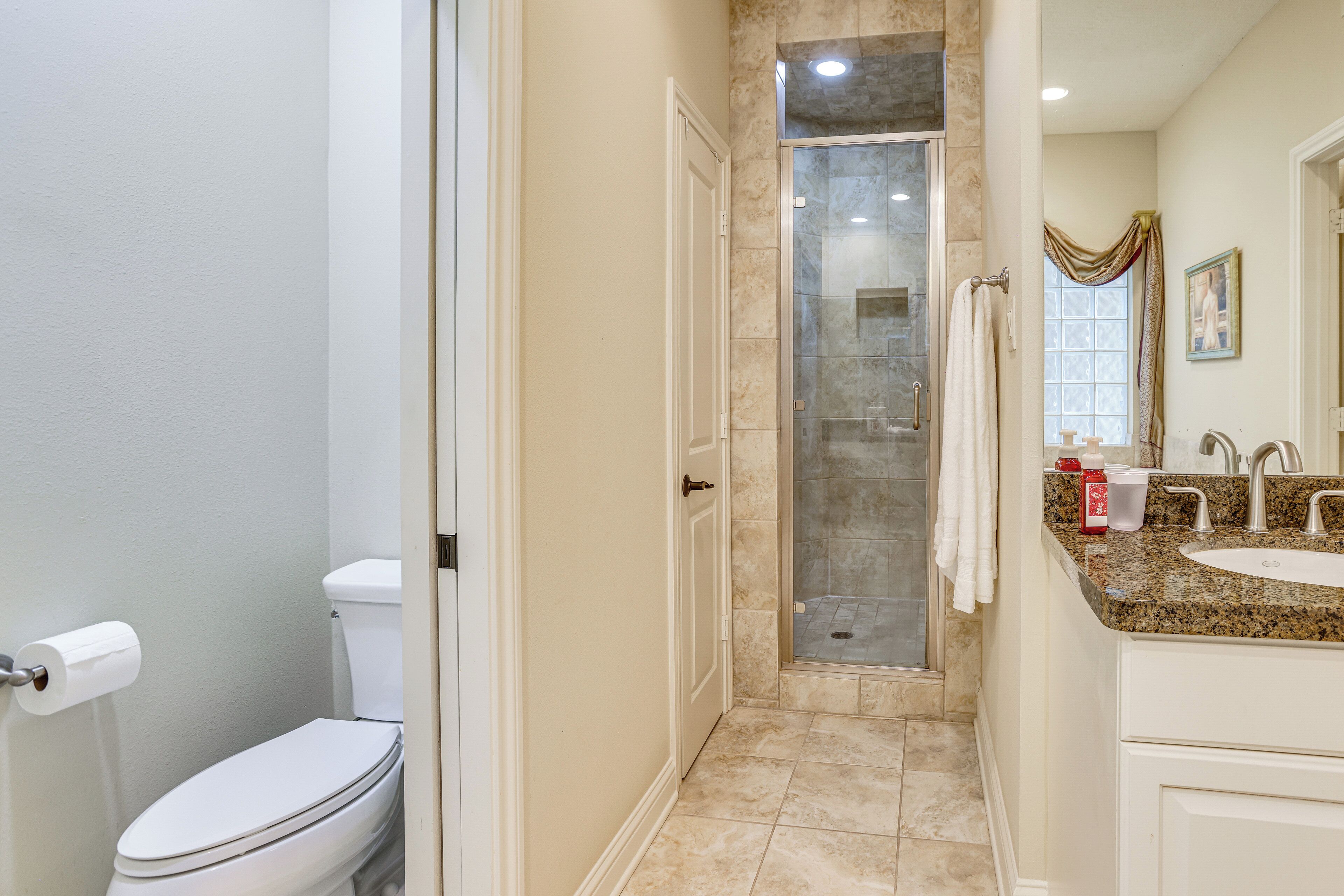 A bathroom with a toilet, shower, and sink.