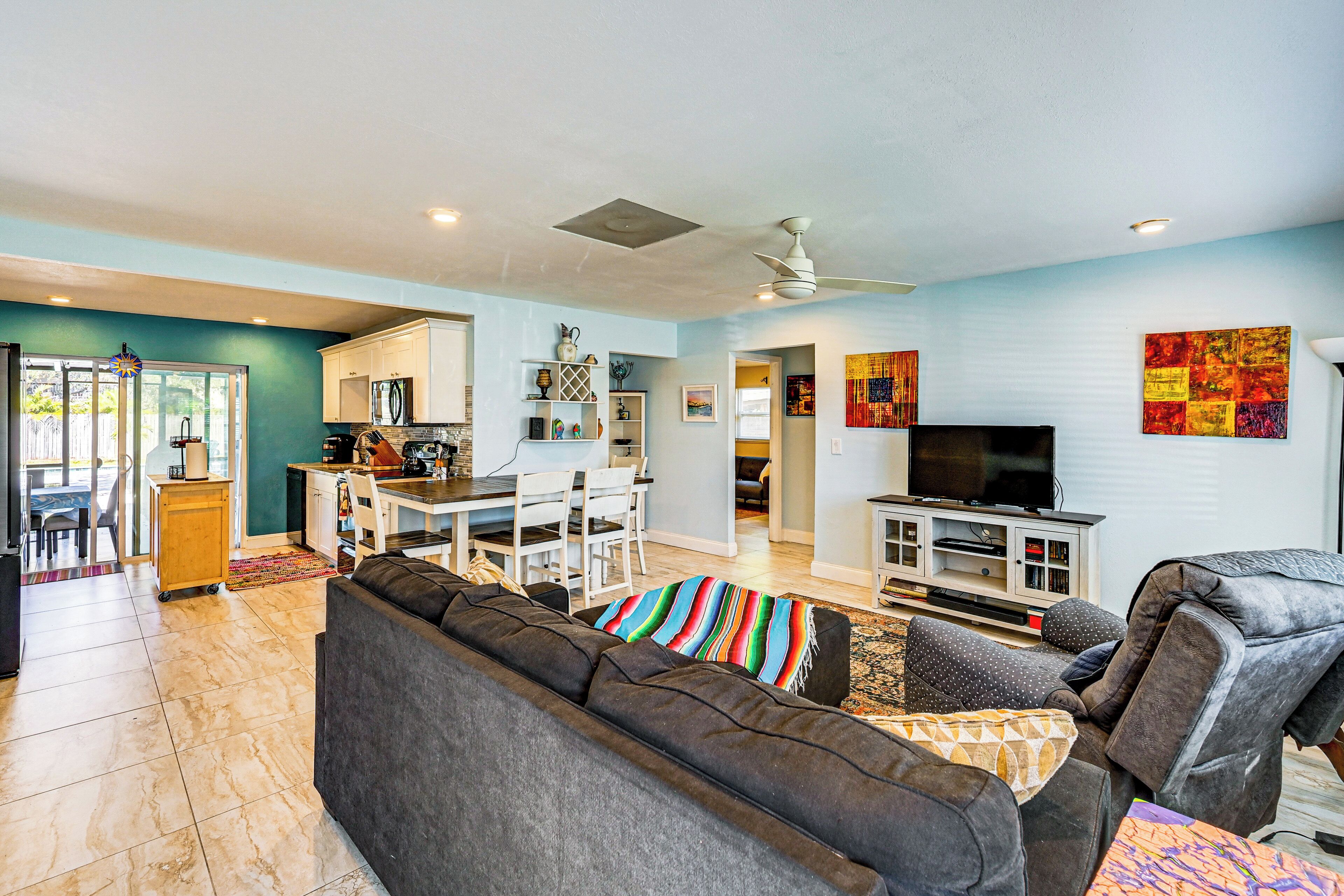 Ein modernes Wohnzimmer mit einem dunkelgrauen Sofa, einem Fernseher und einem Deckenventilator.