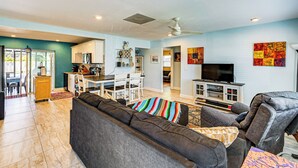 Un salon moderne avec un canapé gris foncé, un téléviseur et un ventilateur de plafond.