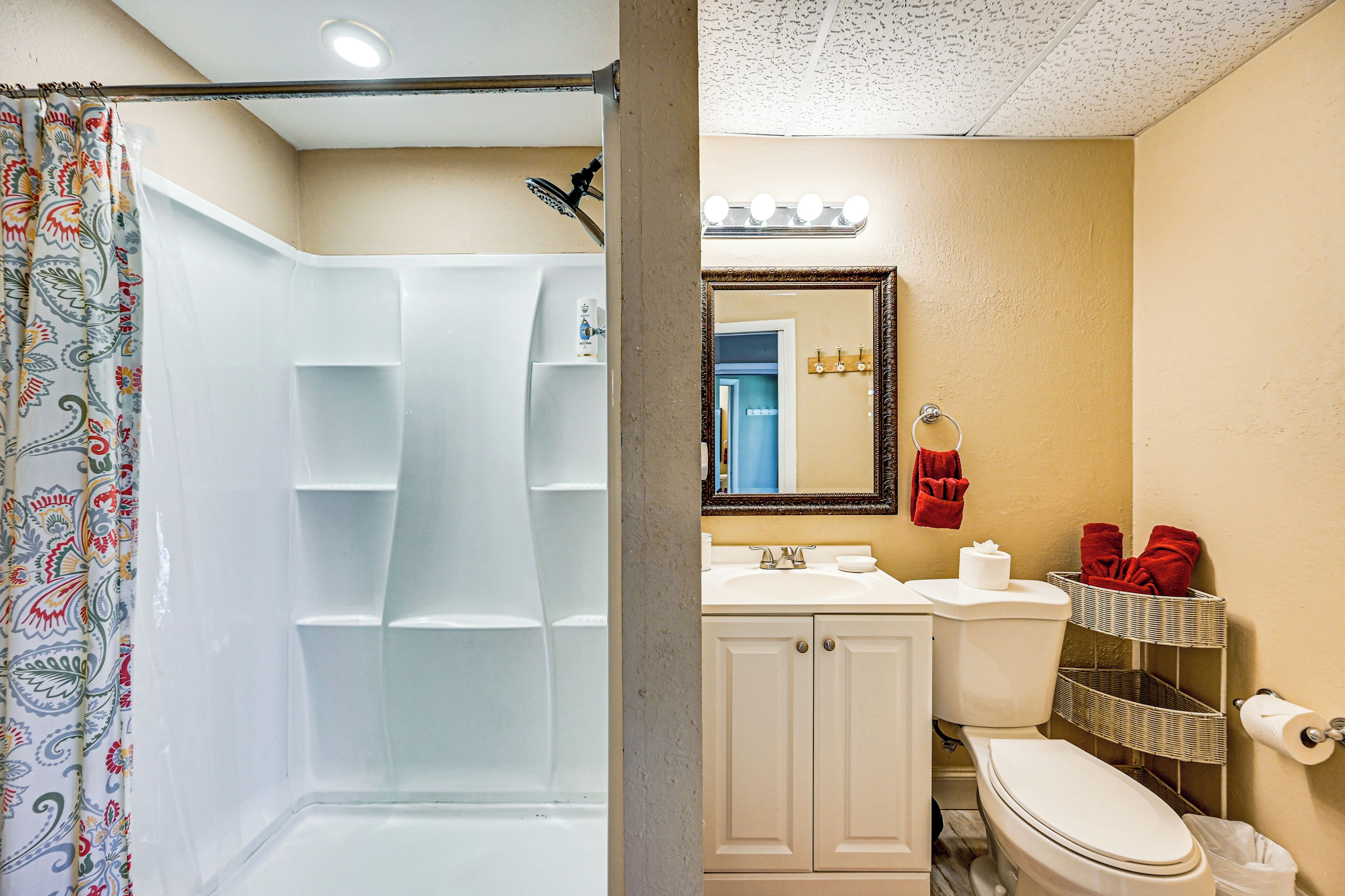 A bathroom with a shower, toilet, sink, and a mirror.
