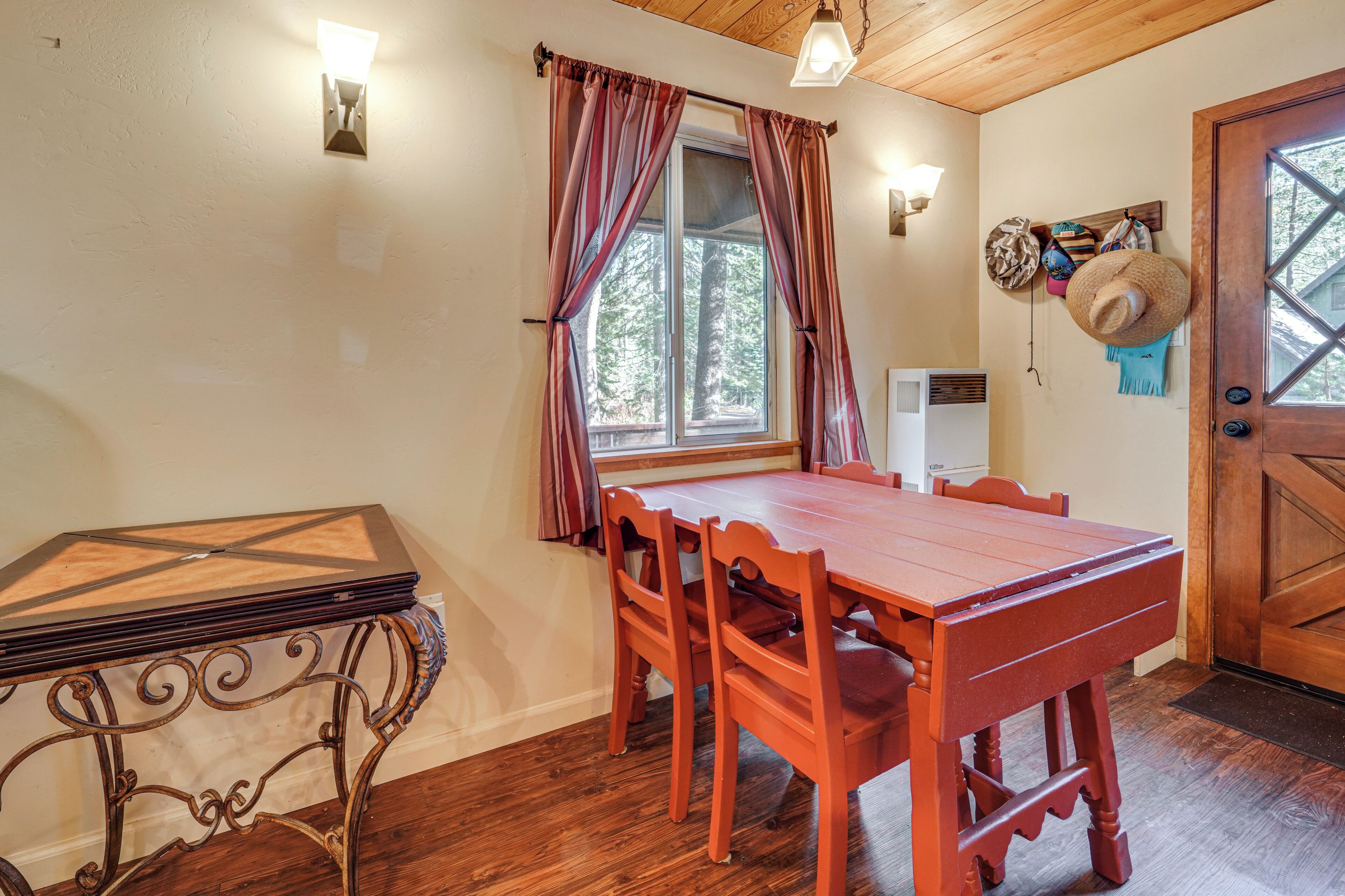 A dining area with a wooden table and chairs, a decorative metal table, a window with curtains, and a door with a glass panel.