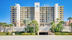 A multi-story hotel with a central tower, balconies, and a flag. - Steps to Shore, Pool Access: New Smyrna Beach Gem! (New Smyrna Beach)