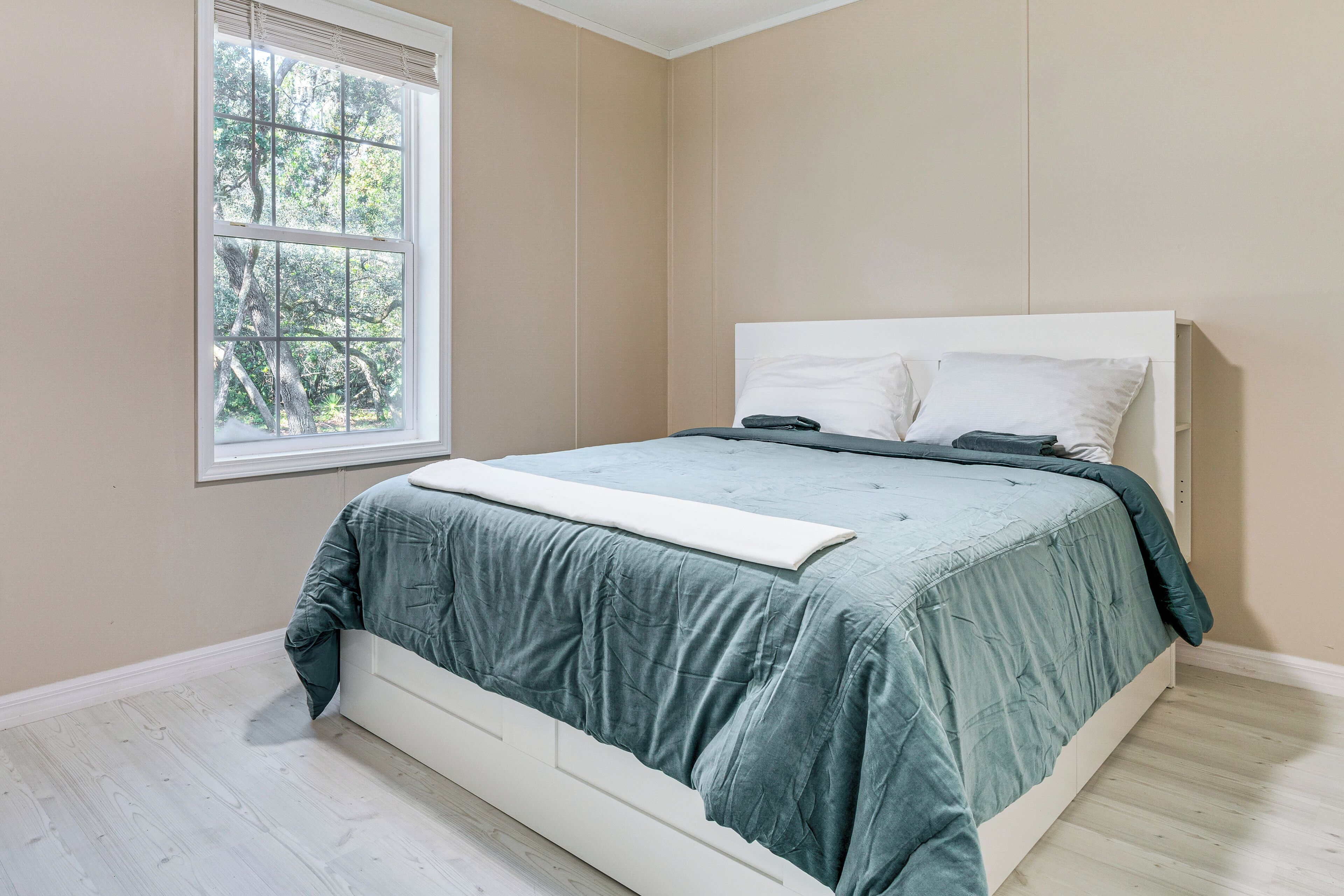 Une chambre à coucher avec un lit, une fenêtre et une vue sur les arbres.
