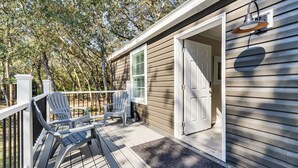 A wooden deck with Adirondack chairs, a door, and a porch light. - 7 Mi to Disney: Pet-friendly Home w/ Yard (Kissimmee)