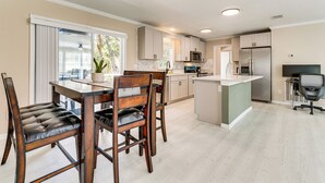A modern kitchen with a dining area, featuring a large island, built-in appliances, and a sliding glass door to the outdoors. - 7 Mi to Disney: Pet-friendly Home w/ Yard (Kissimmee)