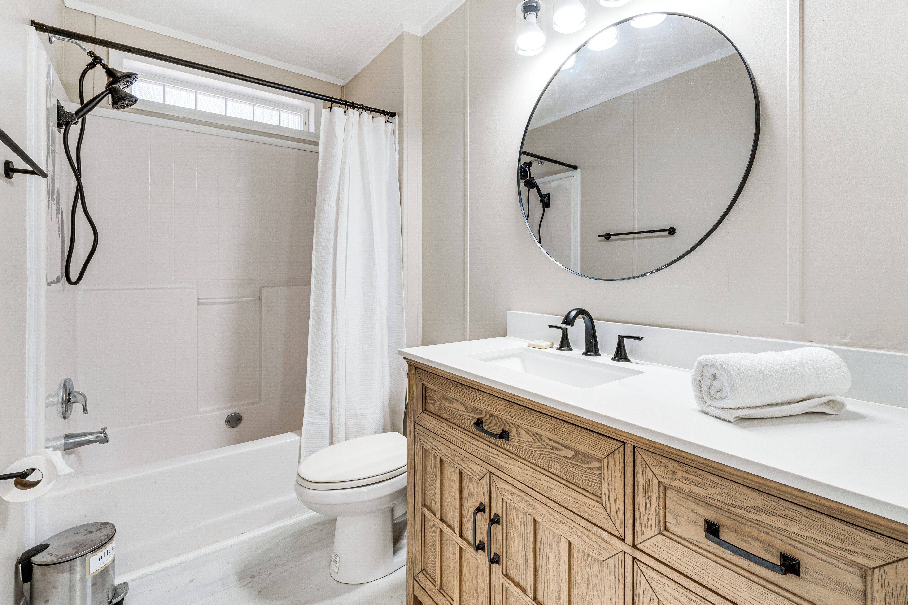 A bathroom with a bathtub, toilet, vanity with a mirror, and a shower area.