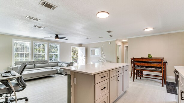 A spacious living area with a large island, a dining table, and a sofa. - 7 Mi to Disney: Pet-friendly Home w/ Yard (Kissimmee)