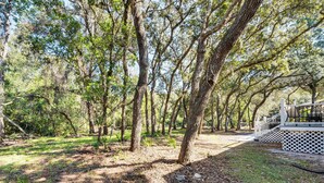 A forested area with a white wooden deck and a staircase leading up to a covered area. - 7 Mi to Disney: Pet-friendly Home w/ Yard (Kissimmee)