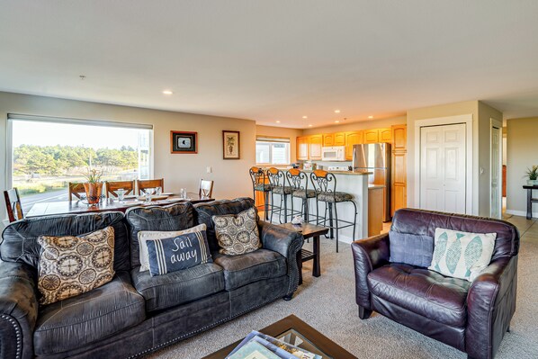 A spacious living room with a leather sofa, a dining area, and a kitchen in the background. - Beach Access & Community Perks! Westport Hideaway (Westport)