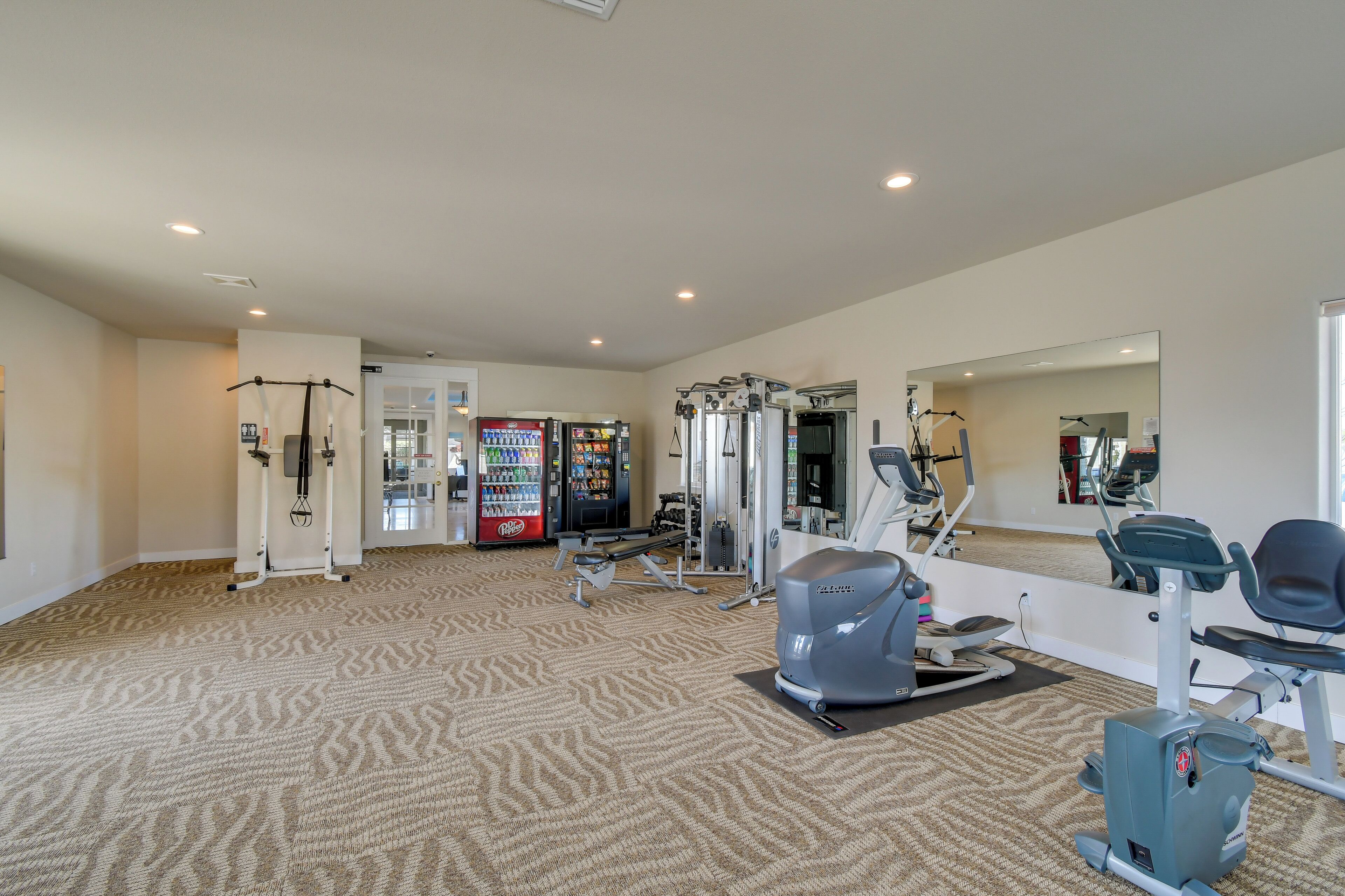 A gym with cardio machines, weightlifting equipment, and a vending machine.