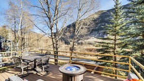 Eine Terrasse mit Gartenmöbeln, einem Feuerkorb und Blick auf eine gebirgige Landschaft.