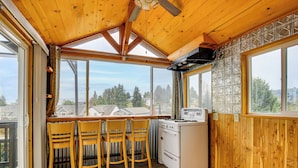 A kitchen with wooden walls, a stove, and a window overlooking a residential area. - 3 Mi to Dtwn Salem: Cozy Gem w/ Sunroom! (Salem)