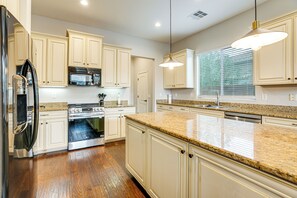 A kitchen with white cabinets, stainless steel appliances, and a granite countertop. - Pool, Views & Ample Space! Sunny Goodyear Retreat (Goodyear)