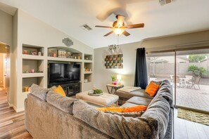 A living room with a large sectional sofa, a flat-screen TV, and a ceiling fan. - San Tan Valley Home Near Hospitals & Hiking! (Queen Creek)