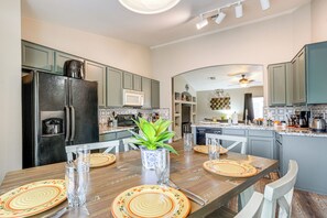 A modern kitchen with a dining area, featuring a refrigerator, microwave, and coffee maker. - San Tan Valley Home Near Hospitals & Hiking! (Queen Creek)