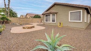 Una casa con un patio, un pequeño jardín con cactus y un cielo despejado.