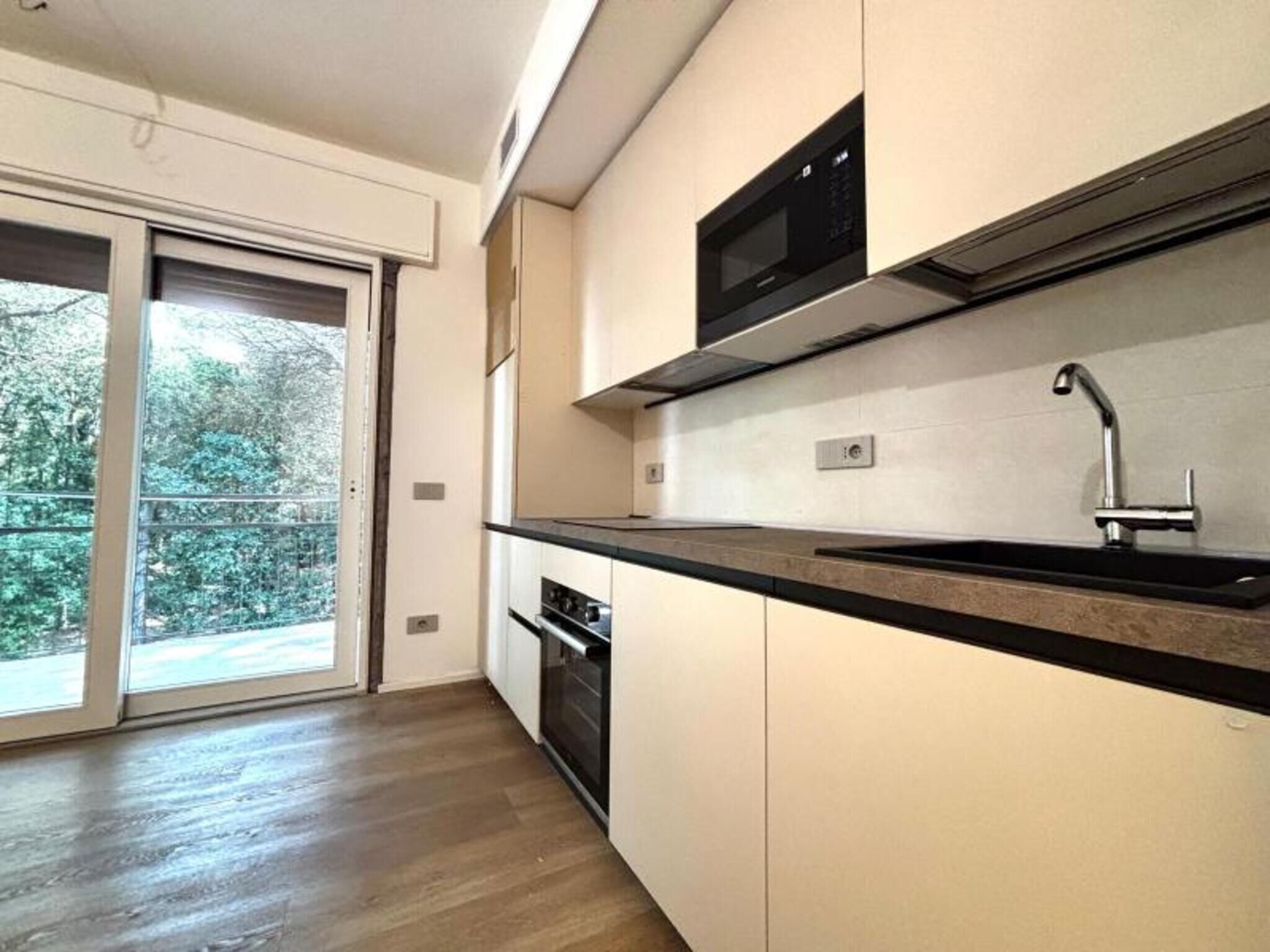 Eine moderne Küche mit schwarzem Arbeitsplatz, Spüle aus Edelstahl und einer Mikrowelle.