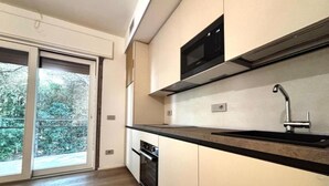 A modern kitchen with a black countertop, stainless steel sink, and a microwave.