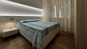 A modern bedroom with a bed, bedside table, and a large window with curtains.