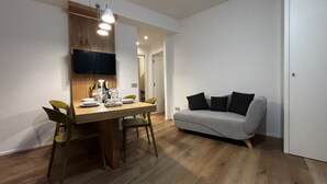 A modern dining area with a wooden table, green chairs, and a grey sofa.