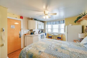 A compact room with a bed, a kitchenette, a dining area, and a ceiling fan. - Walkable Ocean City Studio, Extended Stays (Ocean City)