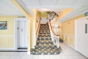 A staircase with a floral carpet, white walls, and a yellow door. - Walkable Ocean City Studio, Extended Stays (Ocean City)