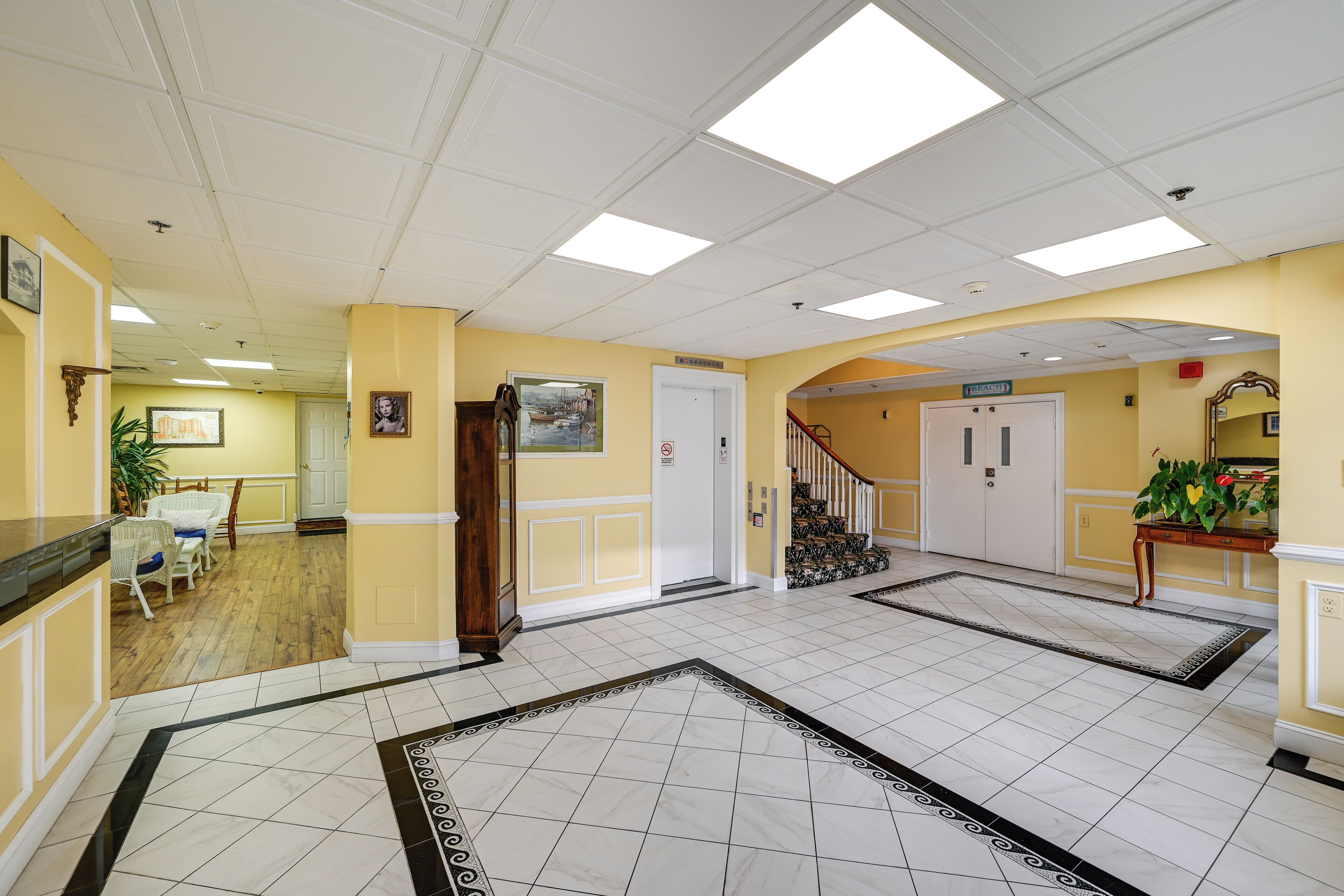 Een hotellobby met een betegelde vloer, een trap en een receptie.
