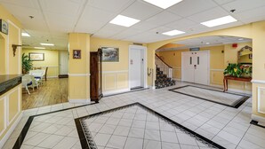 A hotel lobby with a tiled floor, a staircase, and a reception area. - Bay & Bridge Views! Walkable Ocean City Condo (Ocean City)