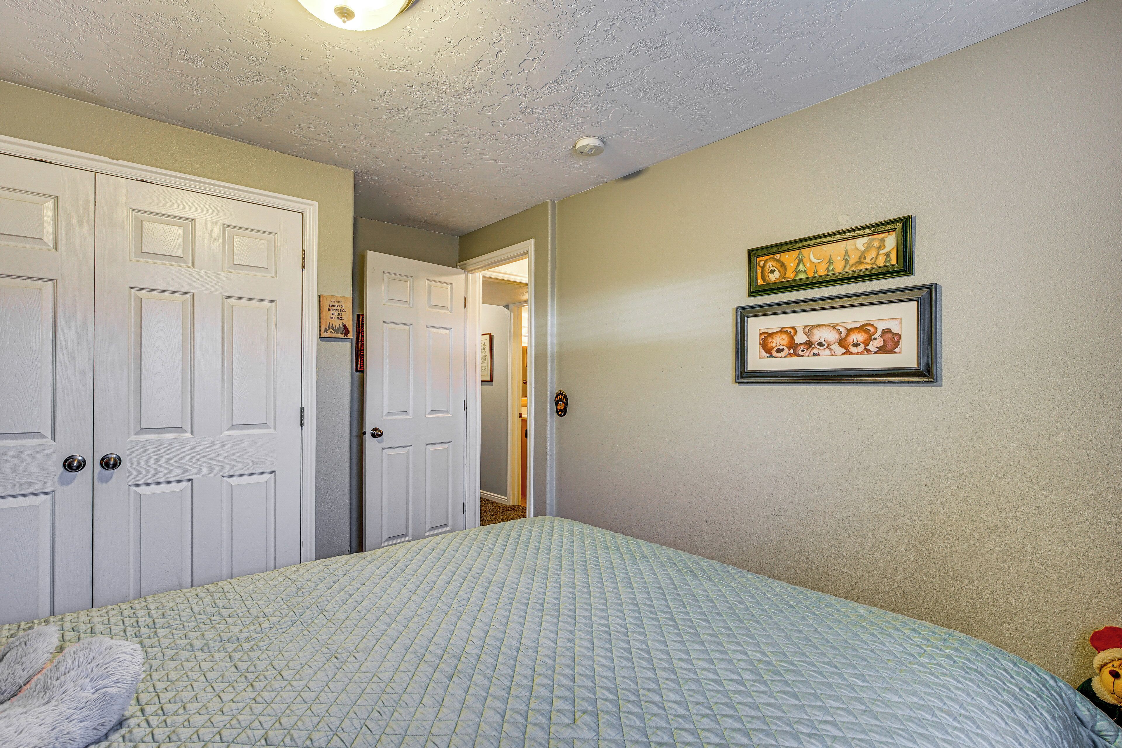 A bedroom with a bed, a door, and two framed pictures on the wall.