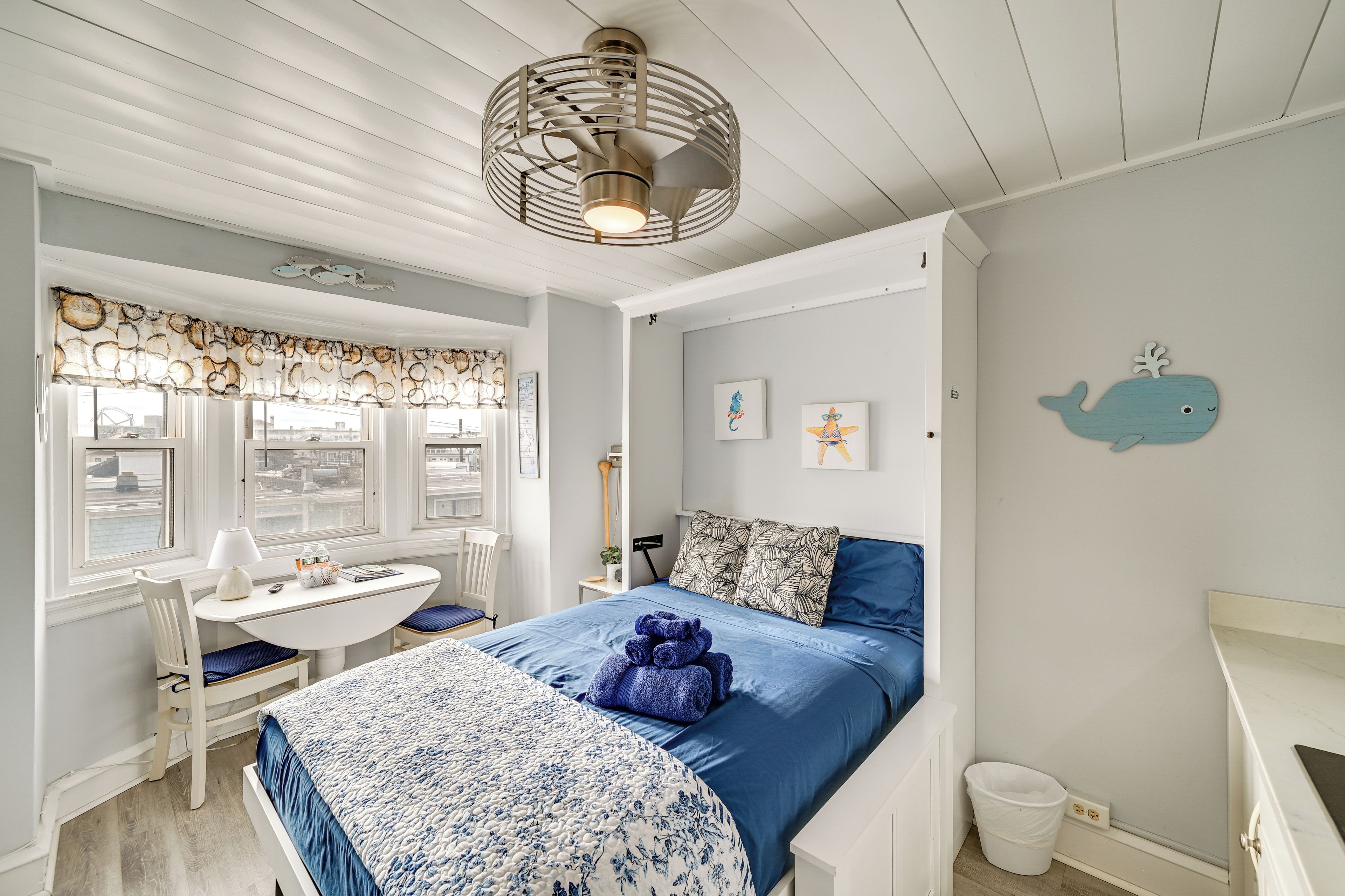 Una habitación con cama, escritorio y ventana con vista al agua.