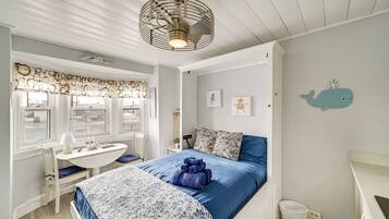 Una habitación con cama, escritorio y ventana con vista al agua.