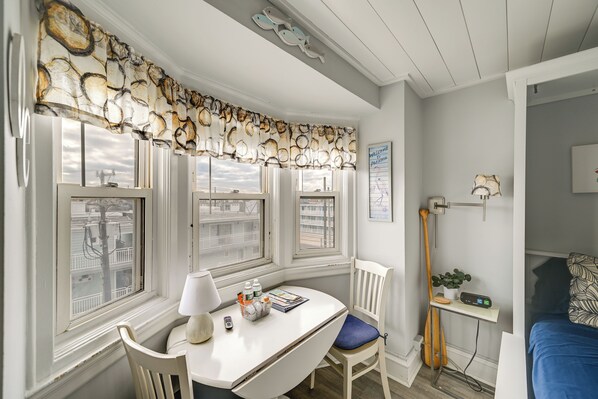 Une pièce avec un bureau blanc, une chaise, une lampe et une fenêtre donnant sur des immeubles.