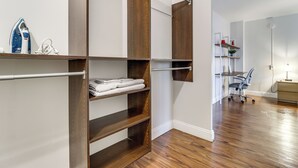 A walk-in closet with open shelves and a hanging rod, a desk with a chair, and a floor lamp. - 2 Mi to DMC & Children's Hospital: Modern Studio (Detroit)
