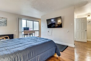 A bedroom with a bed, a TV mounted on the wall, a desk with a chair, and a door. - 2 Mi to DMC & Children's Hospital: Modern Studio (Detroit)