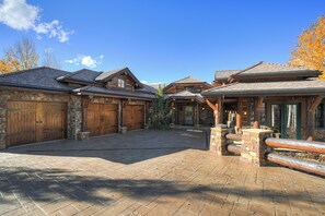 A spacious courtyard with a paved walkway, wooden gates, and stone walls. - Luxury Home, Massive Views, Pool Table, Hot Tub, Nordic Skiing and Golf (Breckenridge)