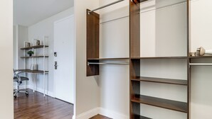 Un dressing avec les portes ouvertes, laissant apparaître des étagères et un espace pour suspendre les vêtements.
