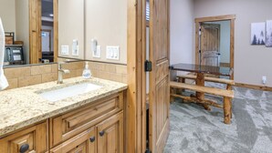 A bathroom with a wooden vanity, a sink, and a large mirror. - Gateway to Yellowstone! Modern Island Park Cabin (Island Park)
