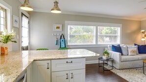 Une cuisine moderne avec des meubles blancs, un plan de travail en granit et des luminaires suspendus.