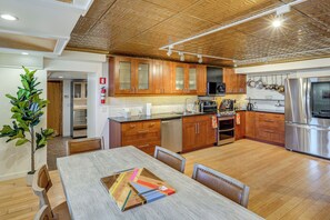 A modern kitchen with wooden cabinets, stainless steel appliances, and a dining area with a wooden table and chairs. - Walk to Athens Riverfront Park! Modern-retro Apt (Athens)