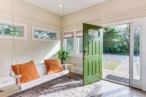 Habitación con un banco blanco, una puerta verde y vistas al exterior.