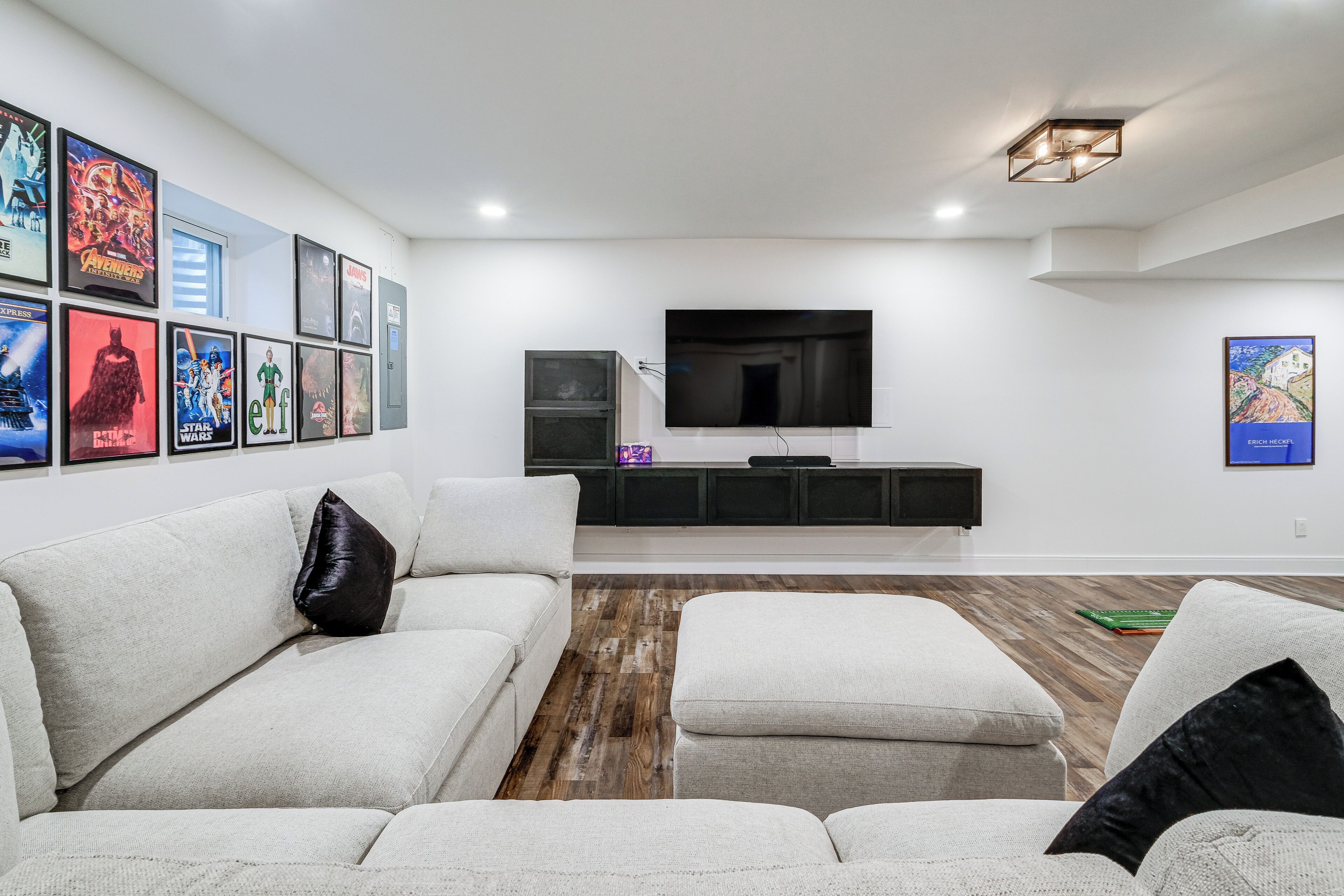 Una sala de estar moderna con un televisor de pantalla plana grande, un sofá blanco y piso de madera.