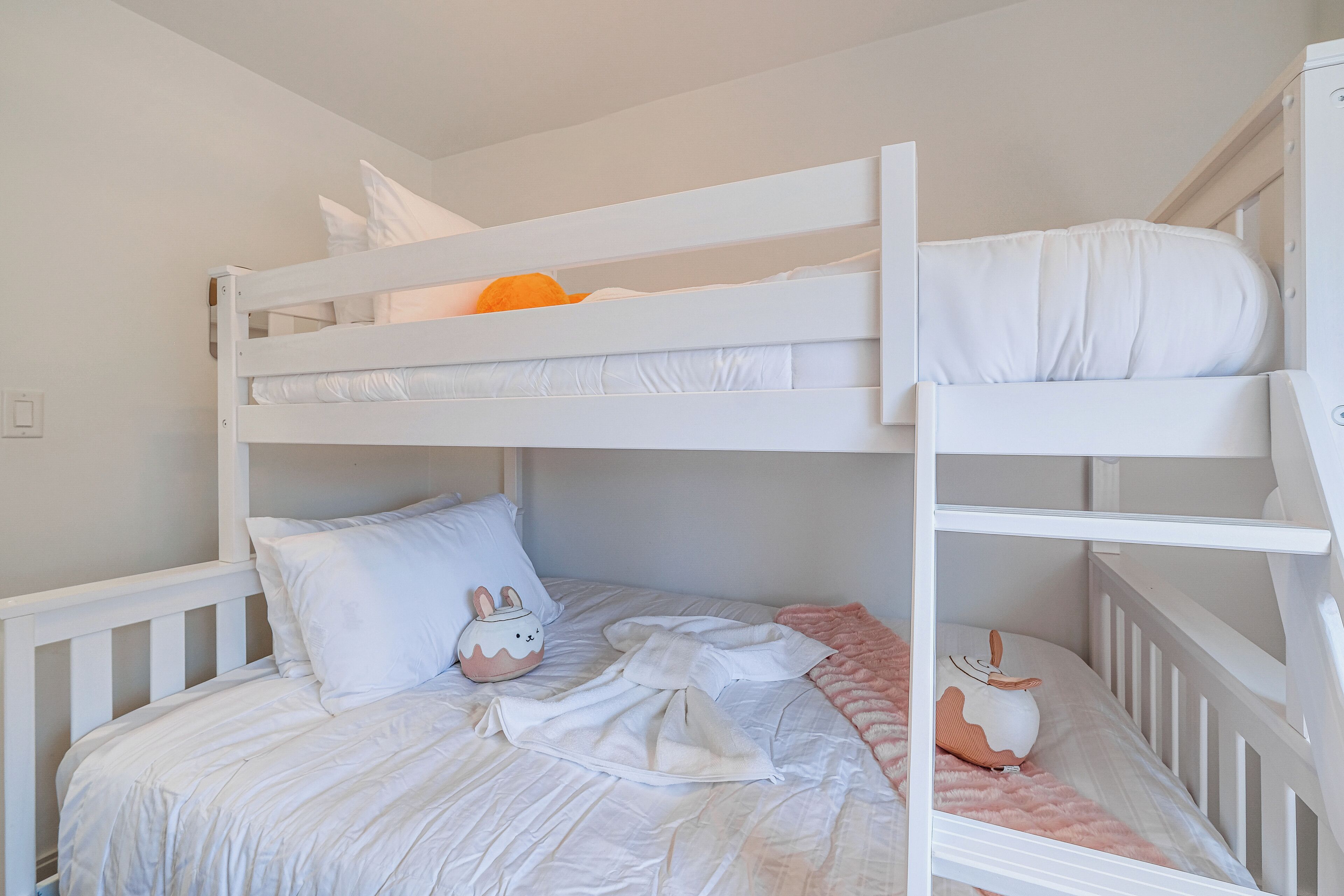 A bunk bed with white bedding and a pink blanket.
