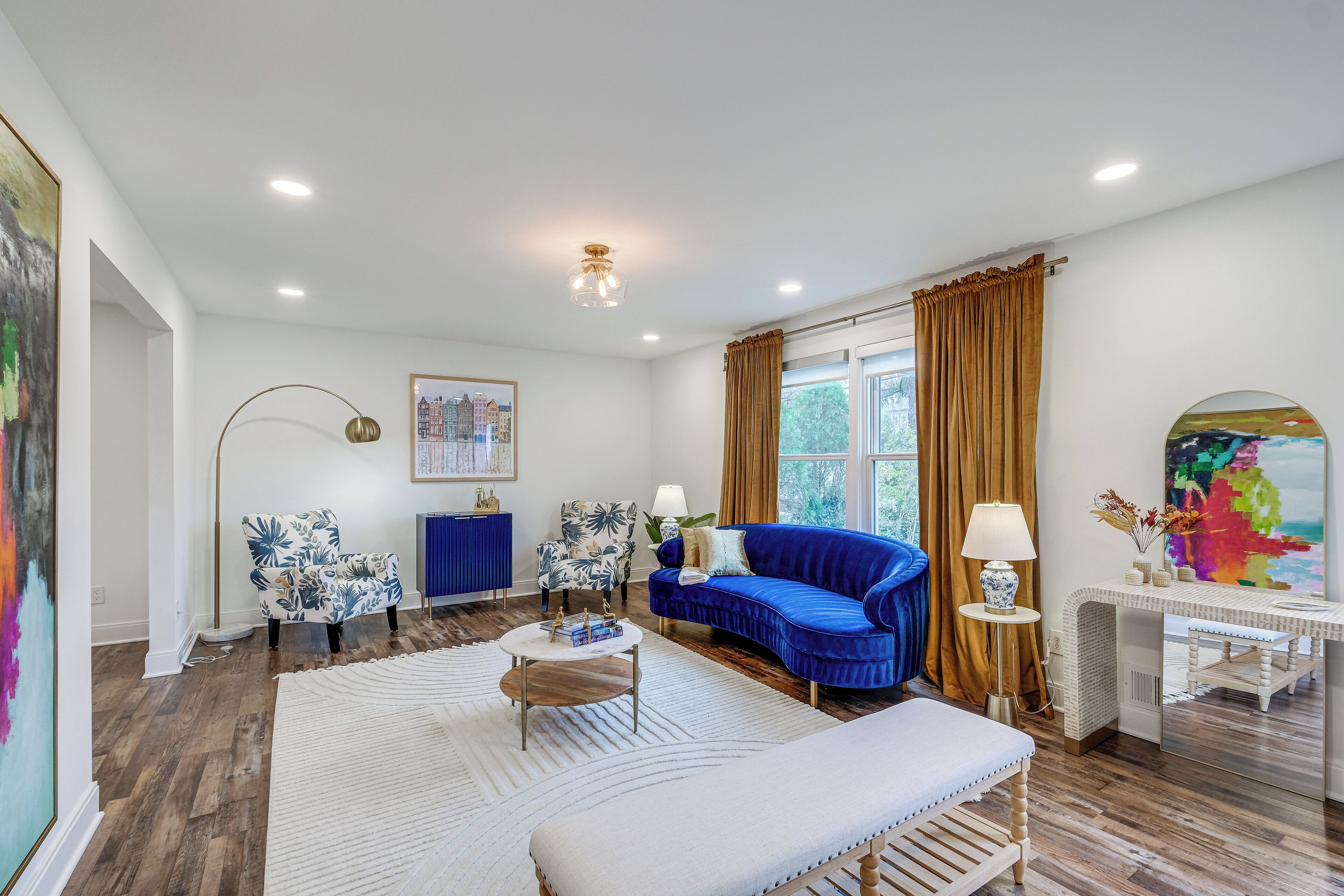 A modern living room with a blue sofa, white armchair, and a round coffee table.